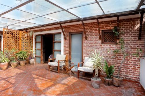 a patio with a glassconservatory with chairs and plants at Hotel Timila in Pātan