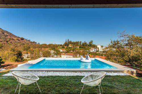 a swimming pool with two chairs in a yard at Casal da serra da Arrábida in Palmela