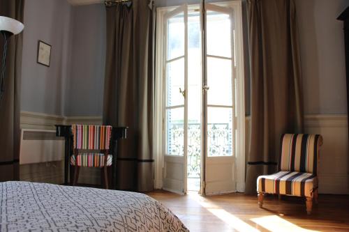sypialnia z łóżkiem i 2 krzesłami przed oknem w obiekcie La Terrasse d'Octave w mieście Saint-Aignan