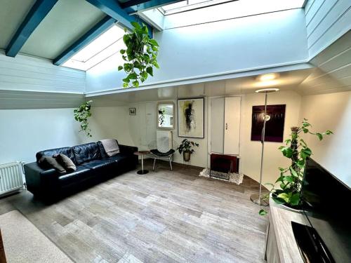 Houseboat in Amsterdam في أمستردام: غرفة معيشة مع أريكة جلدية سوداء في غرفة