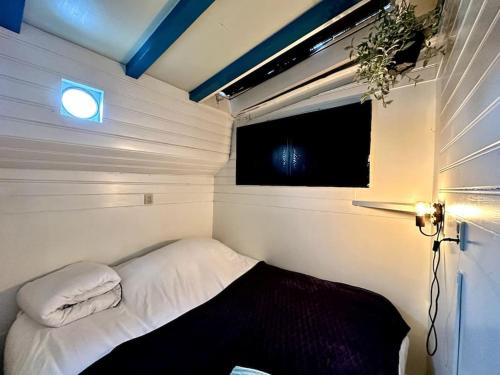 Houseboat in Amsterdam في أمستردام: سرير صغير في غرفة صغيرة مع نافذة