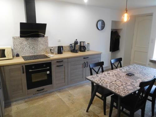 a kitchen with a table and a stove top oven at Charmant Gîte Familial à Gilley, Proche Fayl-Billot et Cite Fortifiée de Langres - FR-1-611-71 in Gilley