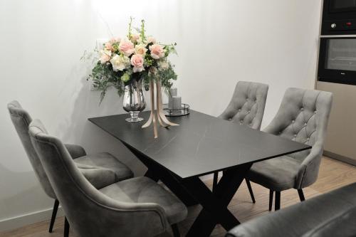 a dining room table with chairs and a vase of flowers at Solaris in Mostar