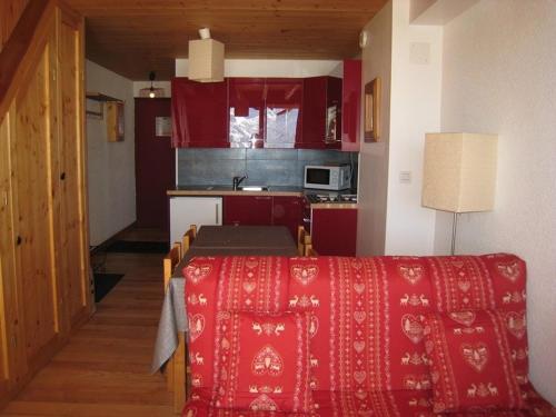 - une cuisine avec des placards rouges et une table dans une pièce dans l'établissement Appartement cosy 5 pers avec balcon sud à l’Alpe d’Huez, skis aux pieds - FR-1-405-28, à L'Alpe-d'Huez