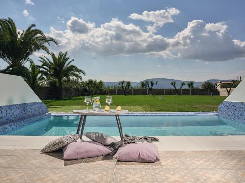 a table with wine glasses and pillows next to a swimming pool at Meandros Boutique & Spa Hotel - Adults Only in Kalamaki