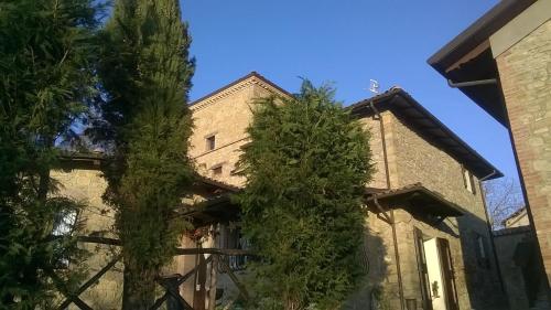 un antiguo edificio con árboles delante de él en Locanda La Posta, en Castel dʼAiano