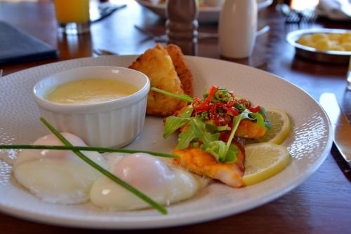 a plate of food with shrimp and a bowl of dipping sauce at Pumula Beach Hotel in Umzumbe