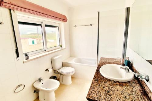uma casa de banho com um lavatório, um WC e uma banheira em Casa da Brisa do Mar em Pataias
