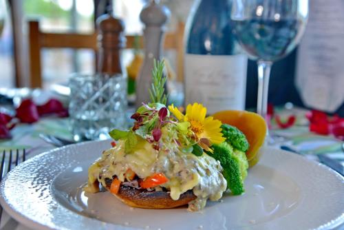 a plate of food with vegetables on a table with a wine glass at Pumula Beach Hotel in Umzumbe
