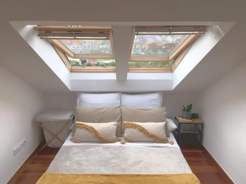 een slaapkamer op zolder met een bed en 2 ramen bij Apartamento céntrico a 50m de la playa in Bueu