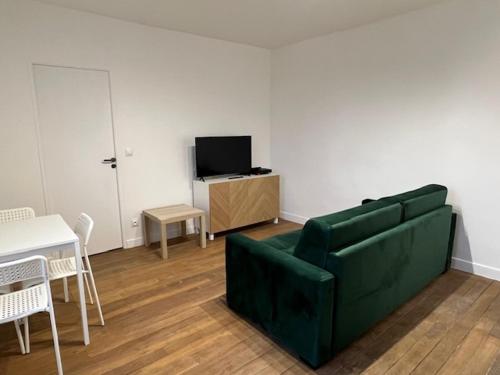 uma sala de estar com um sofá verde e uma mesa em Appartement cosy em Aubervilliers