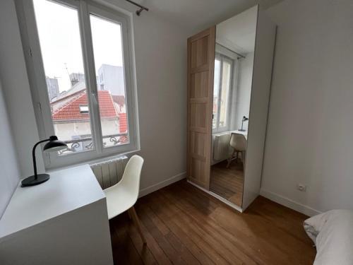 Cette chambre blanche dispose d'un lit, d'un bureau et d'une fenêtre. dans l'établissement Appartement cosy, à Aubervilliers