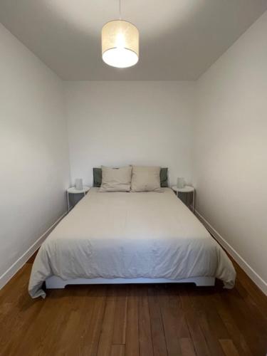 - une chambre blanche avec un lit et deux tables dans l'établissement Appartement cosy, à Aubervilliers