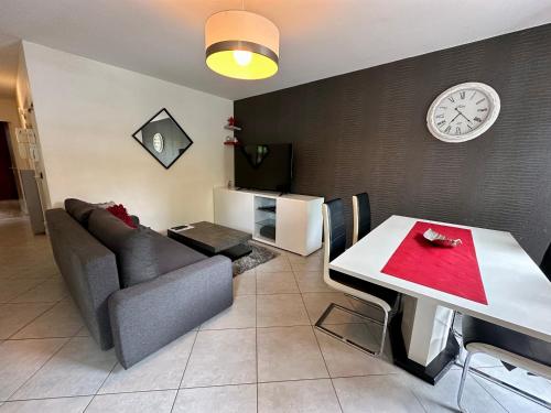 un soggiorno con divano, tavolo e orologio. di Appart’ calme - 48m² - proche Versailles - Paris a Élancourt