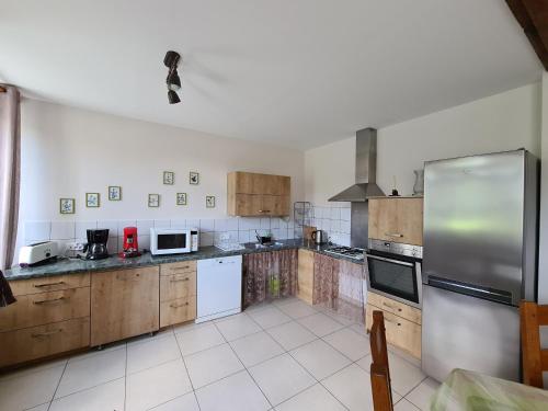 a kitchen with wooden cabinets and a stainless steel refrigerator at Gîte familial en ferme avec jardin, proche forêt et canal d'Orléans - Label Tourisme et Handicap - FR-1-590-7 in Chailly-en-Gâtinais