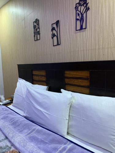 a bed with white pillows and pictures on the wall at Sunrise Rest House in Islamabad