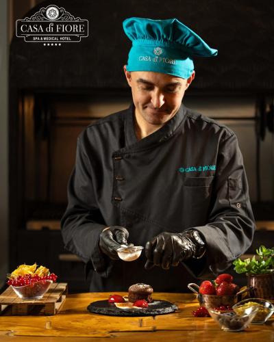 a man in a chefs hat is preparing food at Casa di Fiore SPA and Medical Hotel, Mineral Pools & Private Beach in Kranevo