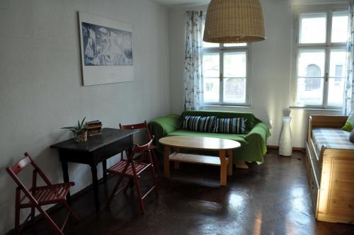 a living room with a green couch and a table at Apartmán u Mlsného medvěda in Bečov nad Teplou
