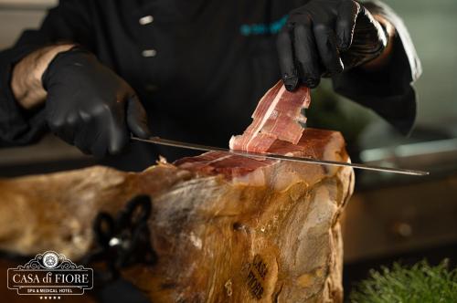 a person cutting a piece of meat with a knife at Casa di Fiore SPA and Medical Hotel, Mineral Pools & Private Beach in Kranevo