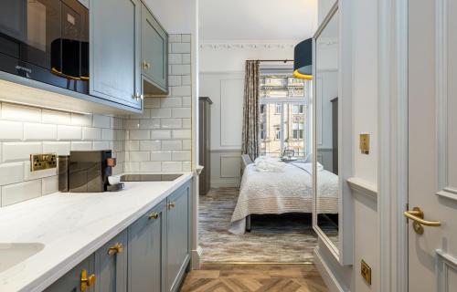 uma cozinha com armários azuis e uma cama num quarto em RÌGH Residences - George Street em Edinburgo