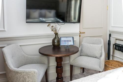 a small table with two chairs and a vase on it at RÌGH Residences - George Street in Edinburgh