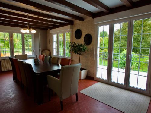 une salle à manger avec une table, des chaises et des fenêtres dans l'établissement Gîte de charme avec sauna, bain nordique et parc arboré au cœur des Vosges - FR-1-589-13, à Colroy-la-Grande