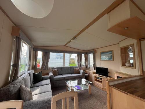 a living room with a couch and a table at B8, Three bedroom caravan - California Cliffs, Parkdean Resort, Scratby - Sleeps 8, bed linen, towels plus Wi-Fi included - Pet Friendly - Onsite entertainment and close to the beach! in Scratby