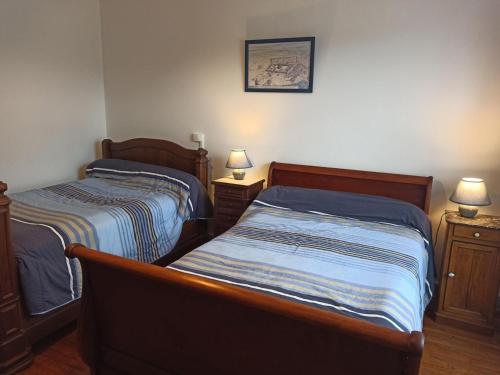 two beds in a small room with two lamps at Gîte convivial avec 3 chambres, proche du patrimoine historique, cour et équipements inclus - FR-1-589-38 in Aouze