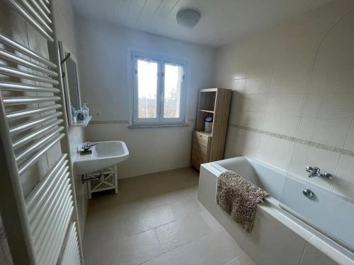 Baño blanco con bañera y lavamanos en Gîte Anould, 3 pièces, 4 personnes - FR-1-589-75, en Anould
