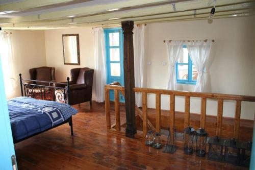 um quarto com uma cama, uma cadeira e janelas em Villa Rustica em Pomoshtitsa