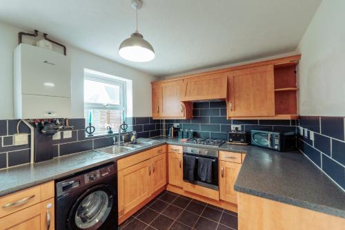 a kitchen with wooden cabinets and a sink and a dishwasher at 2 Bedroom Peaceful Home, Colchester in Mile End