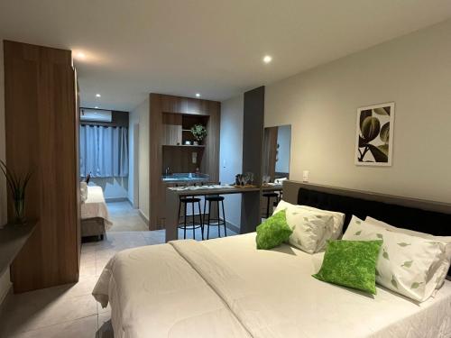 1 dormitorio con 1 cama blanca grande con almohadas verdes en Apart-hotel Nova Friburgo Com café da manhã en Nova Friburgo