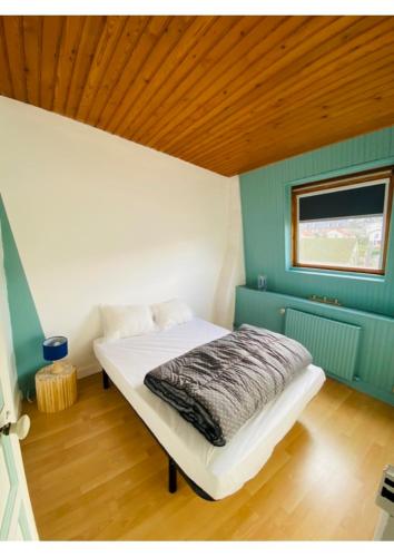 un lit dans une chambre avec un plafond en bois dans l'établissement Villa d'Octavie & de Garance, au Tréport