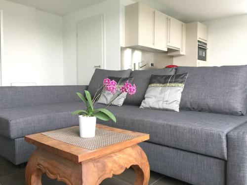 a living room with a gray couch and a table with flowers at Modern little gem close to lake Thun in Reutigen