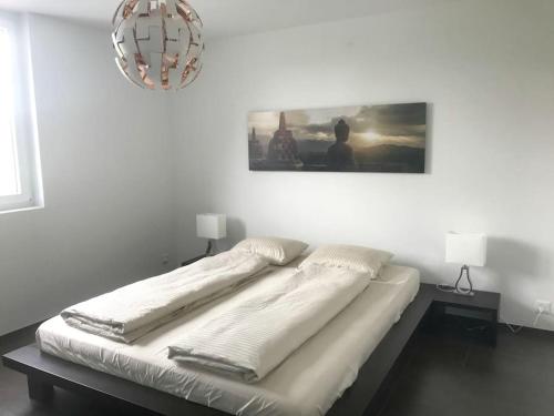 a bed in a white room with a picture on the wall at Modern little gem close to lake Thun in Reutigen