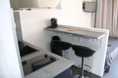 une chambre avec deux tabourets de bar et un comptoir dans l'établissement Studio 103, Héliopolis FGH au village naturiste, au Cap d'Agde