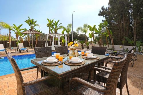 uma mesa de jantar com cadeiras ao lado de uma piscina em Villa Lara - 3bed Bangalow with Large Pool em Agia Napa