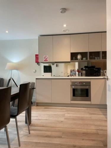 a kitchen with white cabinets and a table with chairs at Modern 2Bed 2Bath with Balcony next to DLR Station in London