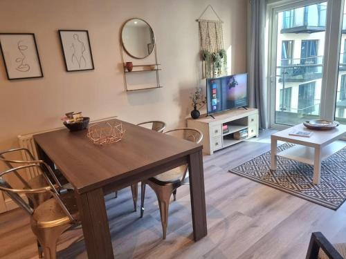 a living room with a wooden table and a television at 2Bed 2Bath -Pool, Balcony, Gym Lift in London
