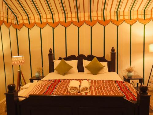 a bedroom with a bed with two sandals on it at Venture Desert Camp Jaisalmer in Sām