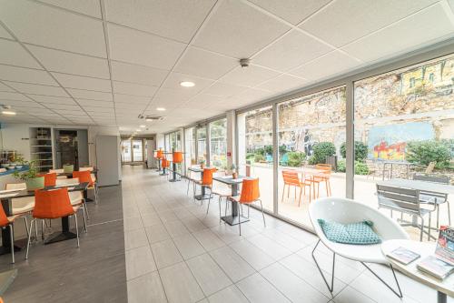 eine leere Cafeteria mit Tischen, Stühlen und Fenstern in der Unterkunft Montempô Marseille Centre Dôme in Marseille