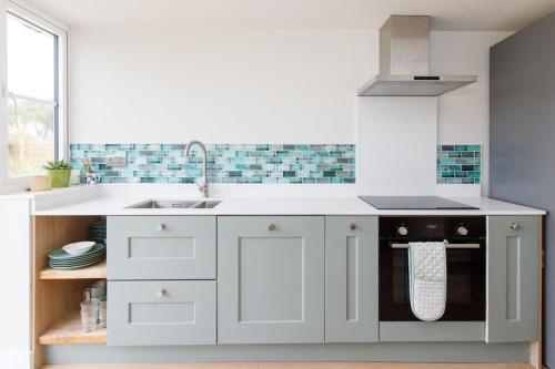 a white kitchen with a sink and a dishwasher at Mariners: Stylish Beachside Getaway with Sea Views in East Wittering