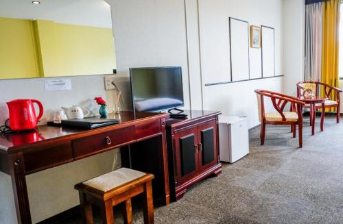 a room with a desk with a television and chairs at 双龍居ホテル in Miki