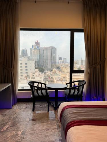 a room with a table and chairs and a large window at Amfas Suites اجنحة امفاس in Manama