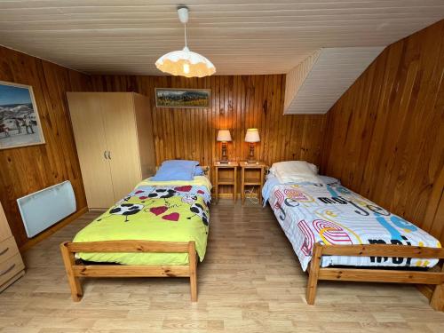 Duas camas num quarto com paredes de madeira em Gîte Taintrux, 4 pièces, 5 personnes - FR-1-589-261 em Taintrux