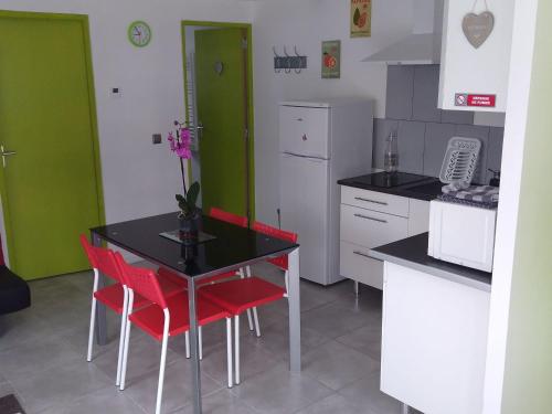 a kitchen with a black table and red chairs at Charmant Gîte Moderne avec Terrasse, Proche Épinal & Nancy, Idéal pour Motards & Randonnées - FR-1-589-262 in Vincey