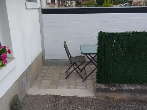 a chair and a table in front of a garage at Charmant Gîte Moderne avec Terrasse, Proche Épinal & Nancy, Idéal pour Motards & Randonnées - FR-1-589-262 in Vincey