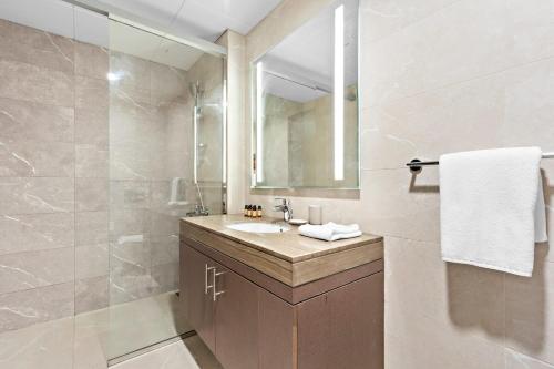 a bathroom with a sink and a shower with a mirror at Silkhaus Chic 1BDR at Najmat Near Reem Central Park in Abu Dhabi