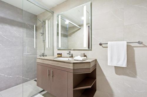 a bathroom with a sink and a shower with a mirror at Silkhaus New 1BDR at Najmat Near Reem Central Park in Abu Dhabi
