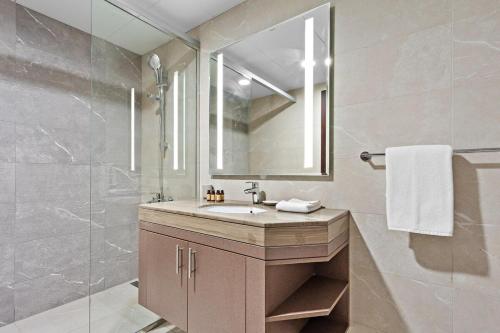 a bathroom with a sink and a mirror and a shower at Silkhaus 1BDR at Najmat Near Reem Central Park in Abu Dhabi